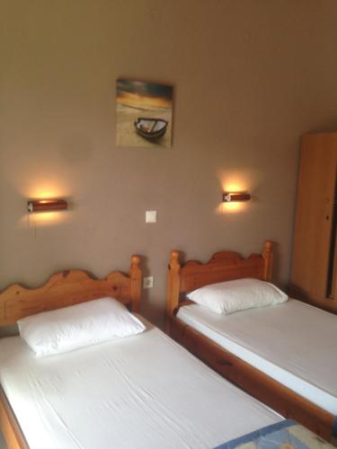two beds in a room with two lamps on the wall at Hebes Studios in Kavos