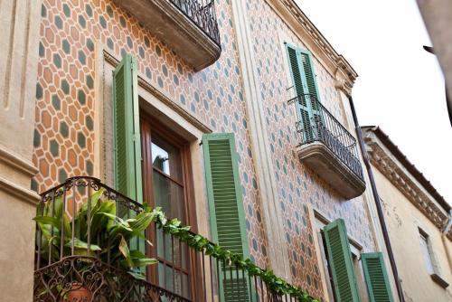 un bâtiment avec des fenêtres vertes à volets et une plante en pot dans l'établissement Hostalet dels Indians, à Begur