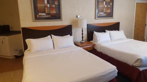 2 Betten in einem Hotelzimmer mit weißer Bettwäsche in der Unterkunft Cedar Park Inn in North Stonington
