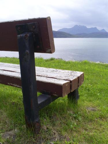 a wooden bench sitting next to a body of water at The Tongue Hotel in Tongue