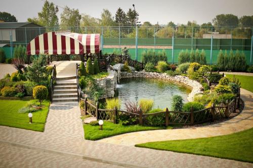 a garden with a pond and a waterfall at Park Hotel Warshawskiy in Sarny