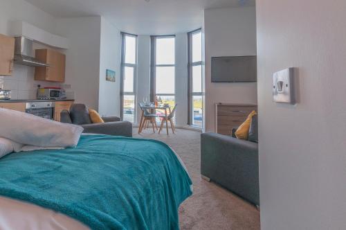 a room with a bed and a kitchen with a table at Fiveway Apartments in Paignton