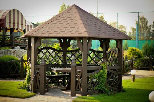 a wooden gazebo with a table and chairs at Park Hotel Warshawskiy in Sarny