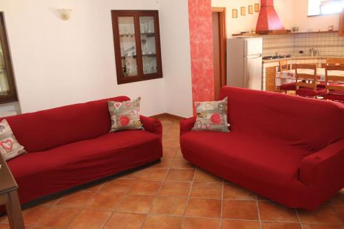 a living room with two red couches and a kitchen at Casa Marilì in Pianillo