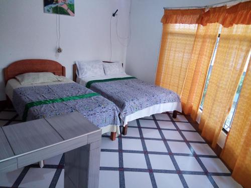 a room with two beds and a table and a window at Sarisa House in Iquitos