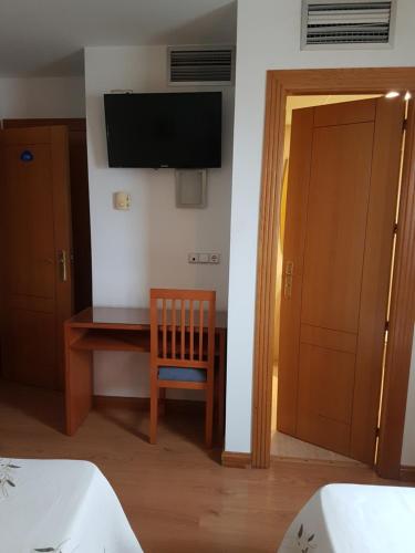 a room with a desk and a television on a wall at Hostal Mediterraneo in El Ejido