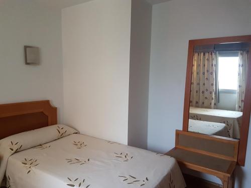 a small bedroom with a bed and a mirror at Hostal Mediterraneo in El Ejido