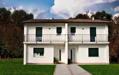 ein weißes Gebäude mit einem Balkon und Gras in der Unterkunft Casablanca in Trebaseleghe