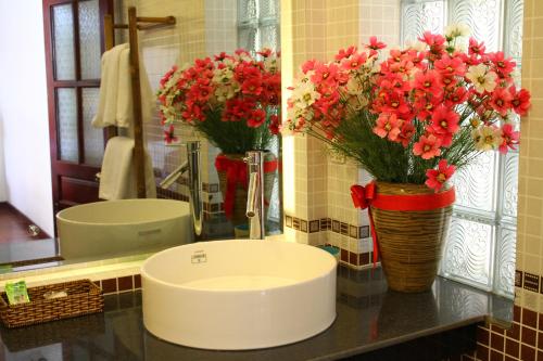 baño con lavabo con flores en un jarrón en The Earth Villa, en Hoi An