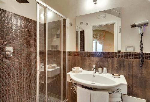 a bathroom with a sink and a glass shower at Relais Antica Badia - San Maurizio 1619 in Ragusa