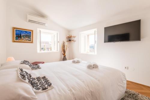 ein weißes Schlafzimmer mit einem Bett mit Handtüchern darauf in der Unterkunft Old Town Duodecim in Dubrovnik