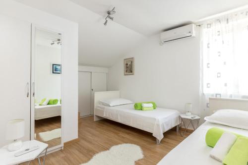a white bedroom with two beds and a mirror at Apartmant Centar Split in Split