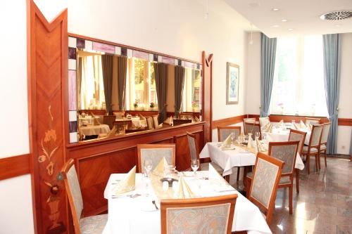 ein Restaurant mit Tischen und Stühlen und einem großen Spiegel in der Unterkunft Hotel Ascania in Aschersleben