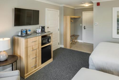 a living room with a bed and a tv on the wall at Center Harbor Inn in Center Harbor