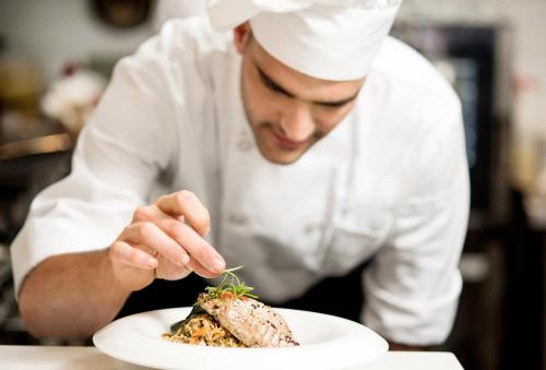 a chef is eating a piece of food on a plate at Elba Vecindario Aeropuerto Business & Convention Hotel in Vecindario