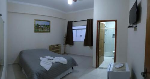 a bedroom with a bed and a mirror and a bathroom at Pousada Circuito das Águas in Caxambu