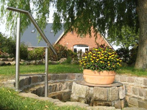 a pot of flowers sitting on a stone wall at Hof Seebrookquelle in Schlesen