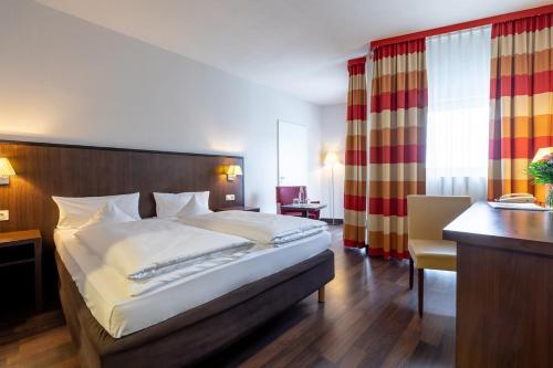 a bedroom with a large bed and a desk and a desk at Trip Inn Frankfurt Nordwestzentrum in Frankfurt/Main