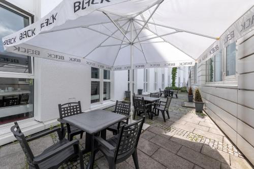 a patio with tables and chairs and an umbrella at Trip Inn Frankfurt Nordwestzentrum in Frankfurt/Main
