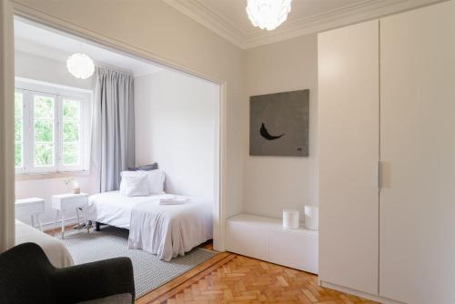 a white bedroom with a bed and a bathroom at Pedrouços 37 in Lisbon