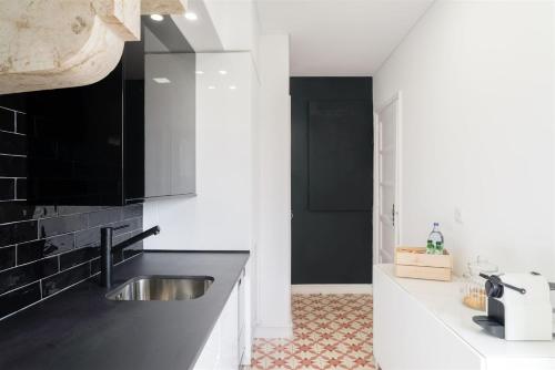 a kitchen with black and white walls and a sink at Pedrouços 37 in Lisbon