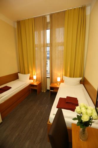 a hotel room with two beds and a vase of flowers at Hotel AI Königshof in Berlin