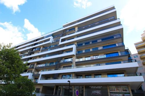 a tall white apartment building with blue windows at Rocha Prime IMO88 in Portimão