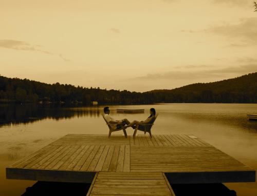 two people sitting on a dock near a body of water at RCNT Chalets Mont-Tremblant in Lac-Superieur