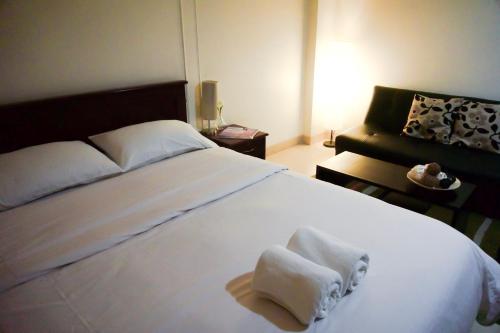 um quarto com uma grande cama branca com toalhas em Baan Boonanan Apartment em Ban Talat Rangsit