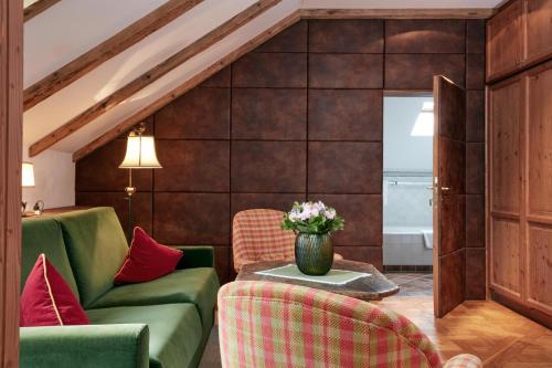 a living room with a green couch and red chairs at Das Bergschlössl - very special in Sankt Anton am Arlberg