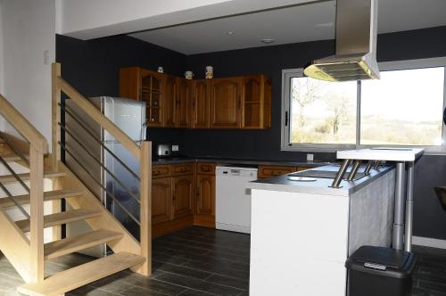 a kitchen with wooden cabinets and a spiral staircase at les gîtes de la cuesta in Henneveux