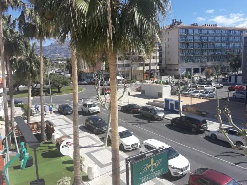 a parking lot with parked cars and palm trees at Albir Sunshine Apartments in Albir