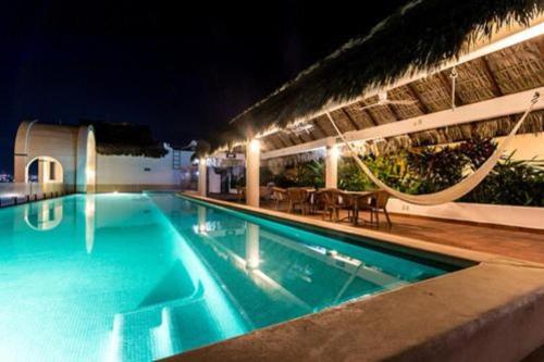 a swimming pool at night with tables and chairs at Hotel Blater in Puerto Escondido