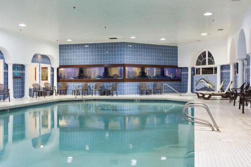 a large swimming pool in a building with tables and chairs at Shilo Inn Suites Ocean Shores in Ocean Shores