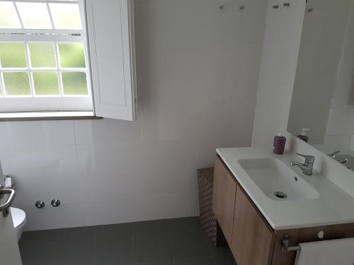 a white bathroom with a sink and a window at StoneWood Lodge AL in São Vicente Ferreira