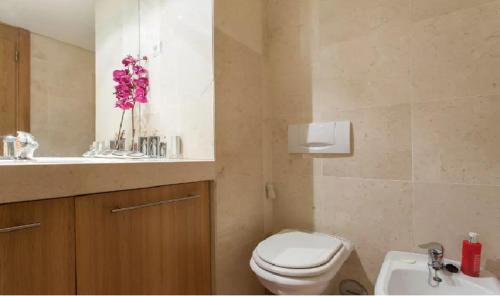 a bathroom with a toilet and a sink with pink flowers at My Oriente in Lisbon