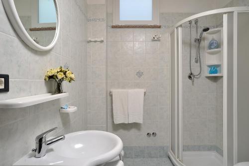 bagno bianco con lavandino e doccia di Hotel Amedeo a Misano Adriatico