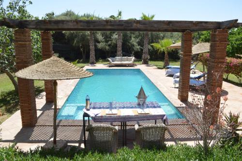 einen Pool mit einem Tisch und einem Sonnenschirm in der Unterkunft Kasbah Gousteau in Taroudant