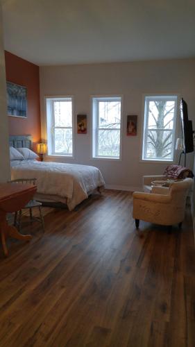 a bedroom with a bed and a table and two windows at Canalside Restaurant & Inn in Port Colborne