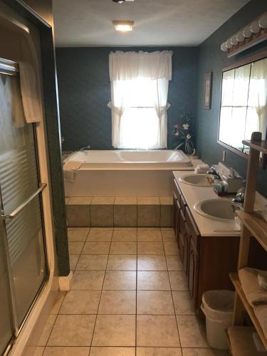a bathroom with a tub and two sinks and a bath tub at Longhouse Manor B&B in Watkins Glen
