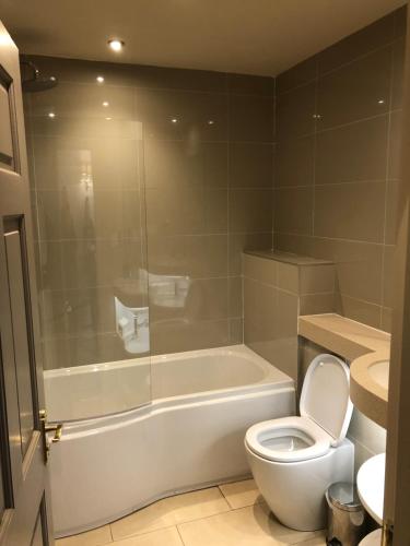 a bathroom with a tub and a toilet and a sink at The Devonshire Grassington in Grassington