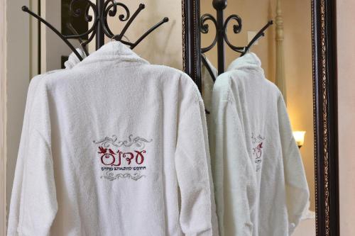 two white jackets hanging in front of a mirror at Eden's Boutique in Had Nes