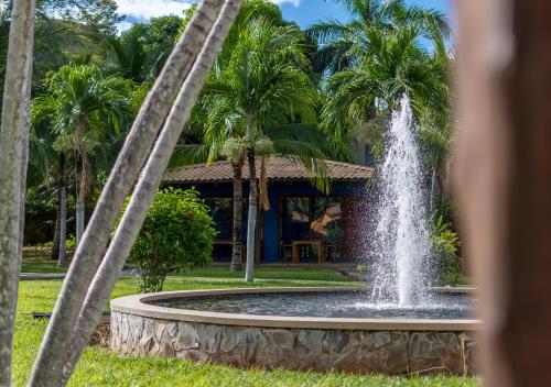 a fountain in front of a house with palm trees at Hotel Guanacaste Lodge in Playa Flamingo