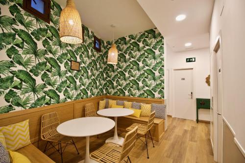 un ristorante con tavoli e sedie e una parete con piante di The Bridge Huertas - Hostal a Madrid