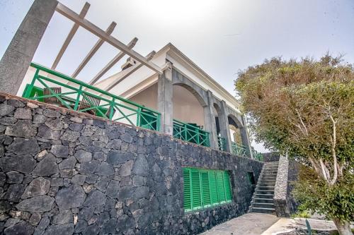 a building with green doors on top of a stone wall at Vista Timanfaya in Yaiza