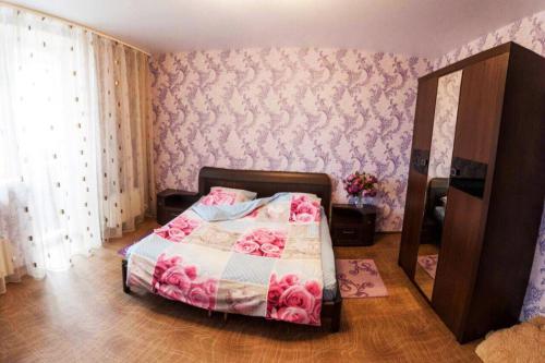 a bedroom with a bed with pink floral wallpaper at Apartment on Gazovikov 41 in Tyumen