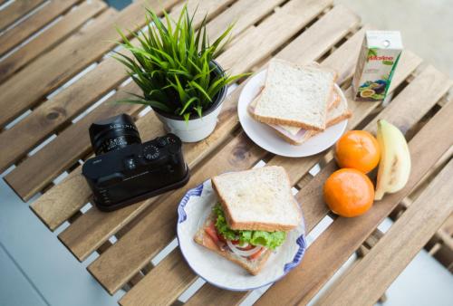 two plates of sandwiches and oranges on a wooden table at Chez Bure - Bure Homestay in Kanchanaburi