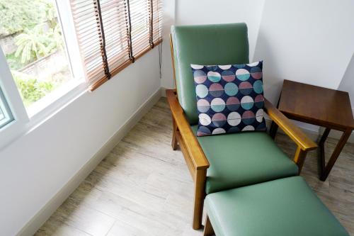 a green chair with a pillow and a table at Chez Bure - Bure Homestay in Kanchanaburi