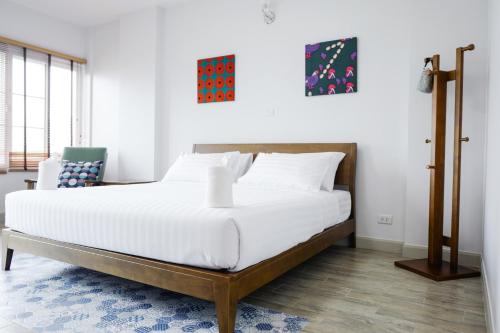 a bedroom with a large bed with white sheets at Chez Bure - Bure Homestay in Kanchanaburi