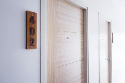 a wooden door in a room with a clock at Chez Bure - Bure Homestay in Kanchanaburi